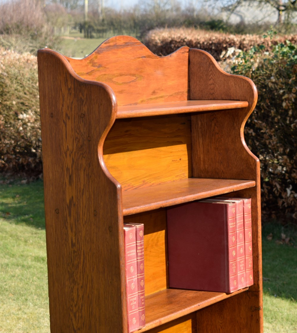 A tall early 20th-century open-front oak bookcase featuring four fixed shelves and a shaped top gallery. View VI