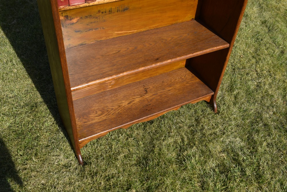 A tall early 20th-century open-front oak bookcase featuring four fixed shelves and a shaped top gallery. View IX