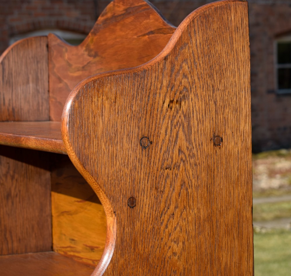 A tall early 20th-century open-front oak bookcase featuring four fixed shelves and a shaped top gallery. View XIV