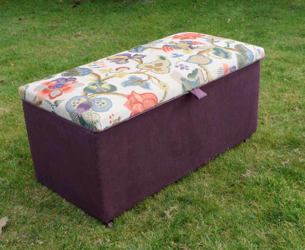 A rectangular Victorian upholstered storage ottoman featuring a deep purple base and a floral patterned fabric lid.
