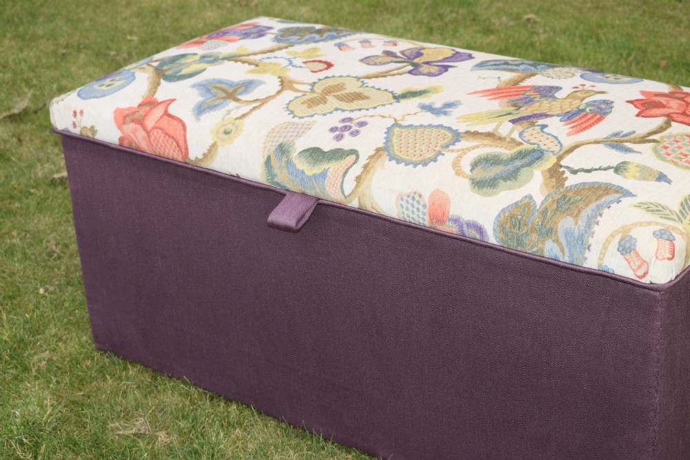 A rectangular Victorian upholstered storage ottoman featuring a deep purple base and a floral patterned fabric lid. View V