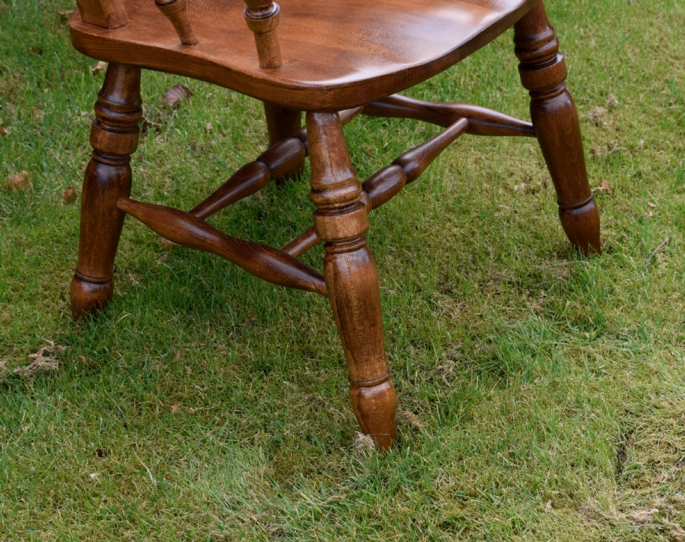 An early 20th-century warm brown wooden country kitchen armchair with vertical back spindles and turned legs. View V
