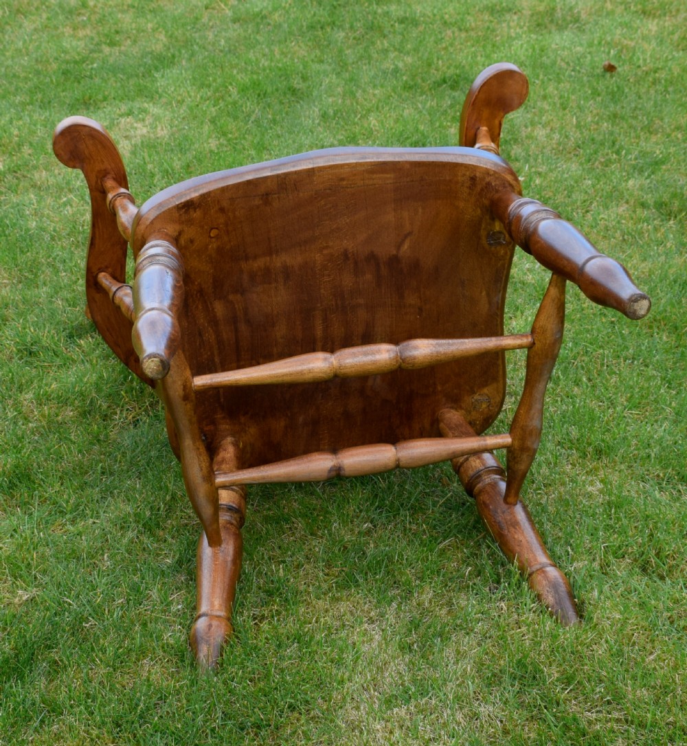 An early 20th-century warm brown wooden country kitchen armchair with vertical back spindles and turned legs. View X