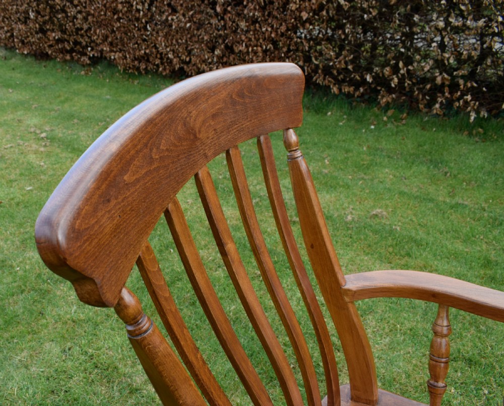 An early 20th-century warm brown wooden country kitchen armchair with vertical back spindles and turned legs. View XI