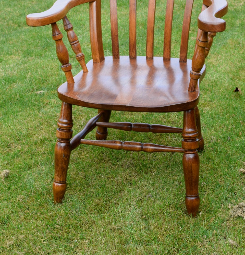 An early 20th-century warm brown wooden country kitchen armchair with vertical back spindles and turned legs. View XIII