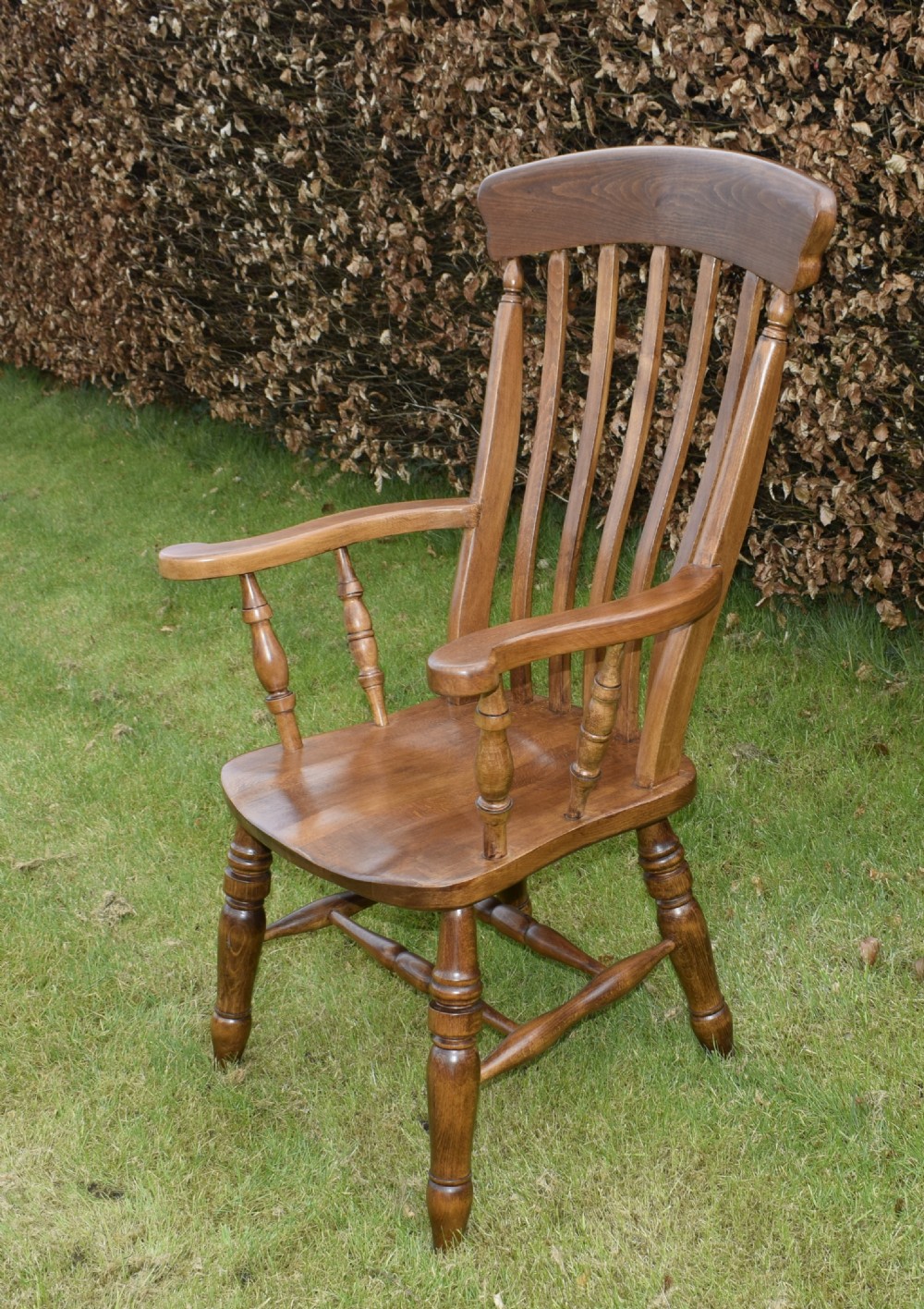 An early 20th-century warm brown wooden country kitchen armchair with vertical back spindles and turned legs. View XVI