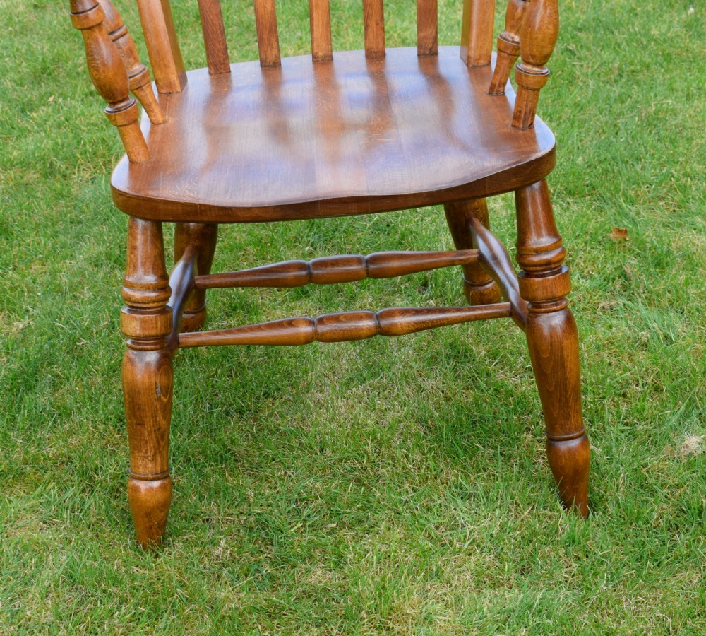 An early 20th-century warm brown wooden country kitchen armchair with vertical back spindles and turned legs. View XVIII