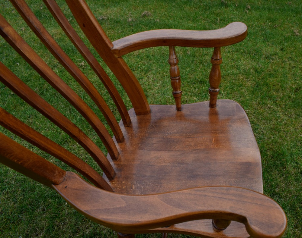 An early 20th-century warm brown wooden country kitchen armchair with vertical back spindles and turned legs. View XX