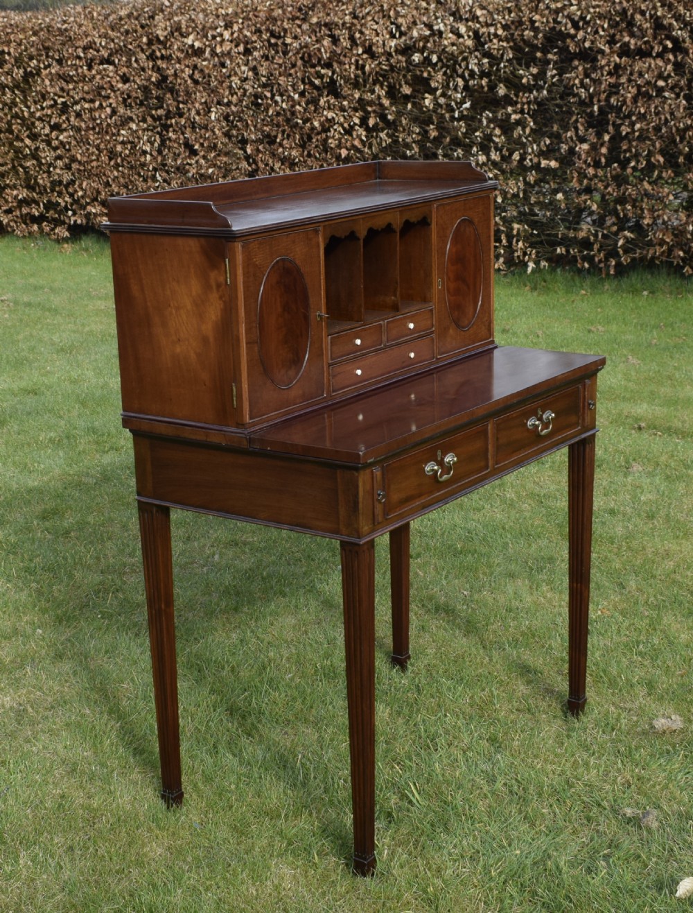 An Edwardian mahogany writing desk featuring a top superstructure with pigeonholes, cupboards, and small drawers above two frieze drawers on fluted tapered legs. View VIII