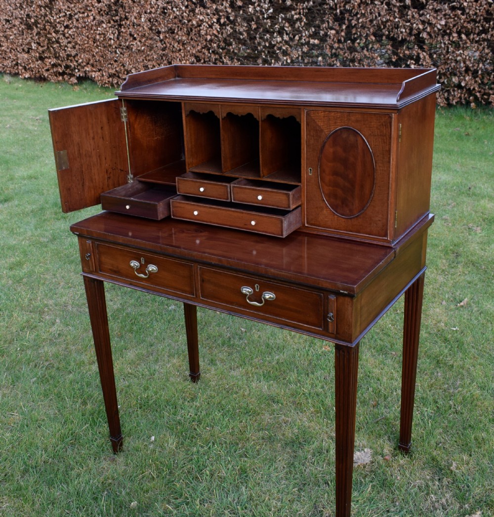 An Edwardian mahogany writing desk featuring a top superstructure with pigeonholes, cupboards, and small drawers above two frieze drawers on fluted tapered legs. View XII