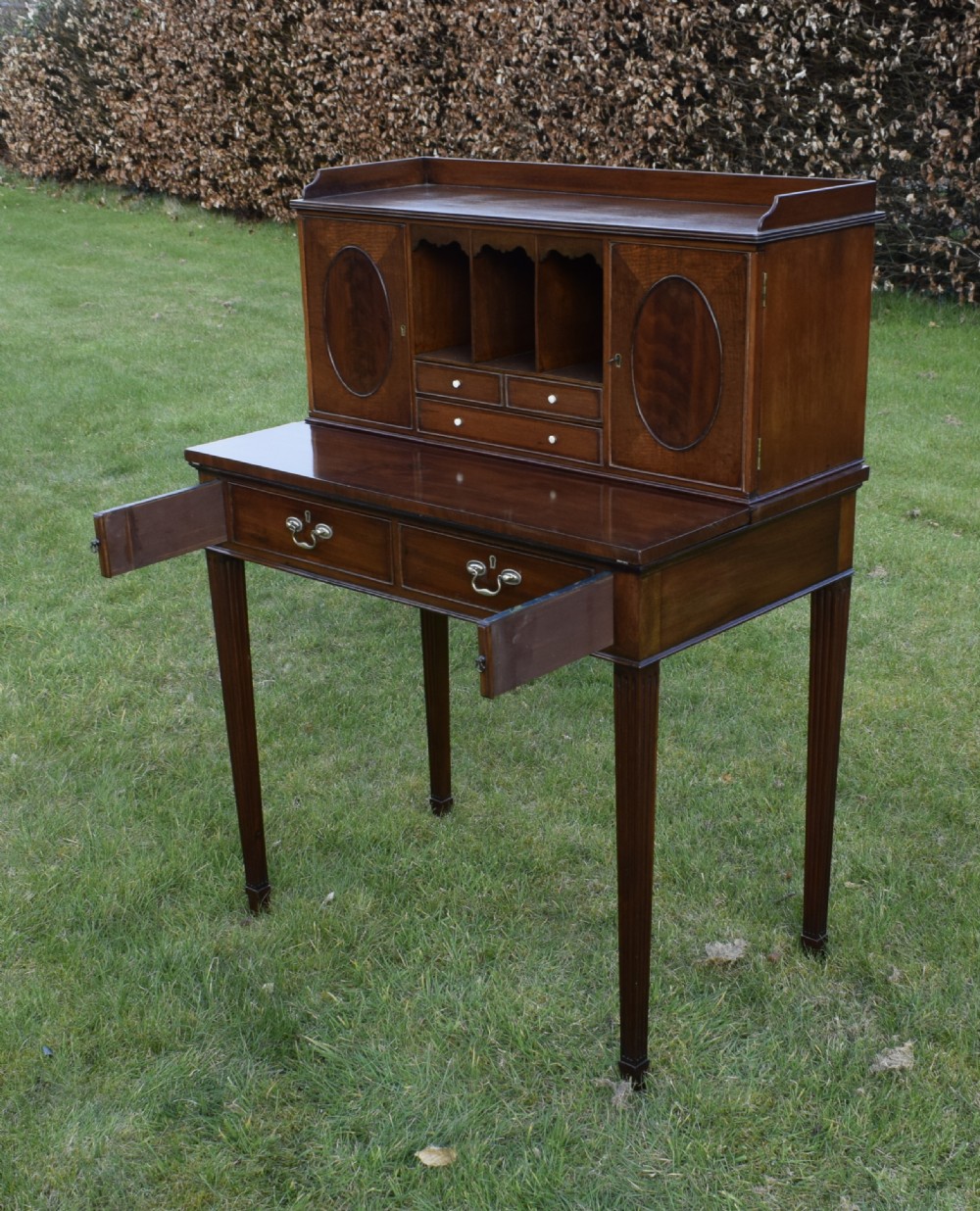 An Edwardian mahogany writing desk featuring a top superstructure with pigeonholes, cupboards, and small drawers above two frieze drawers on fluted tapered legs. View XIII