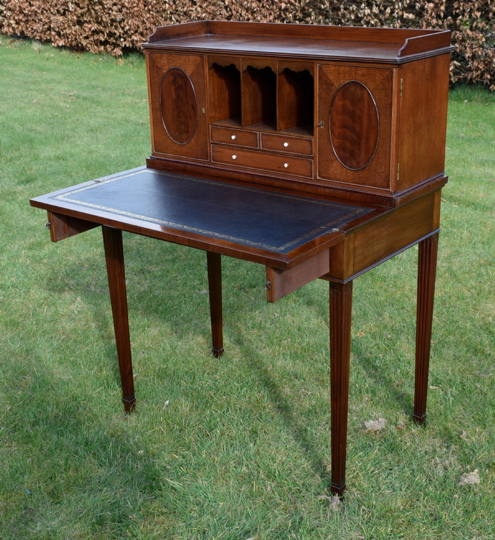 An Edwardian mahogany writing desk featuring a top superstructure with pigeonholes, cupboards, and small drawers above two frieze drawers on fluted tapered legs. View XIV