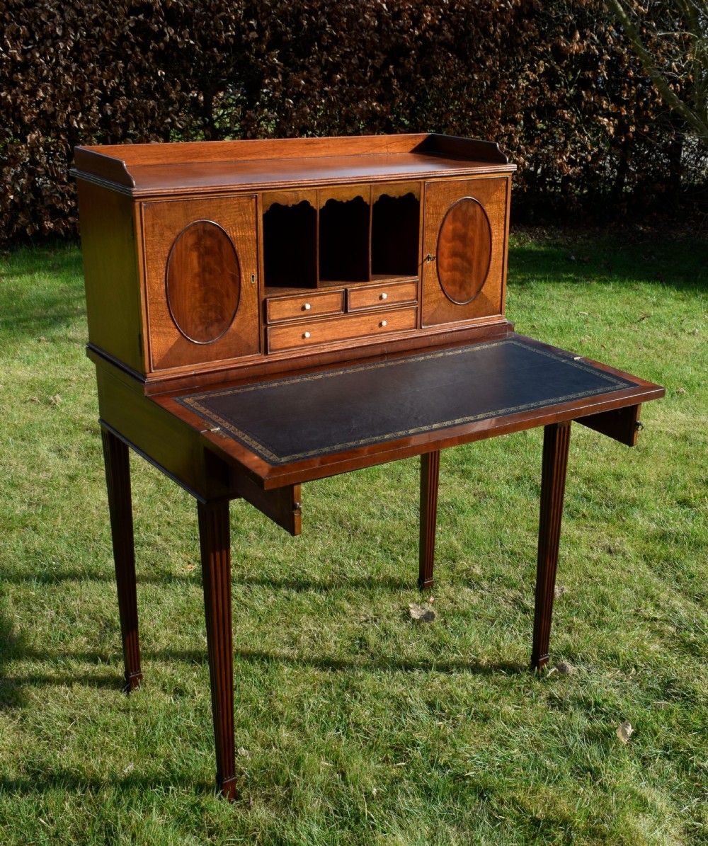 An Edwardian mahogany writing desk featuring a top superstructure with pigeonholes, cupboards, and small drawers above two frieze drawers on fluted tapered legs. View XV