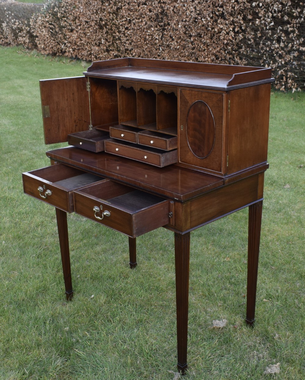 An Edwardian mahogany writing desk featuring a top superstructure with pigeonholes, cupboards, and small drawers above two frieze drawers on fluted tapered legs. View XVIII