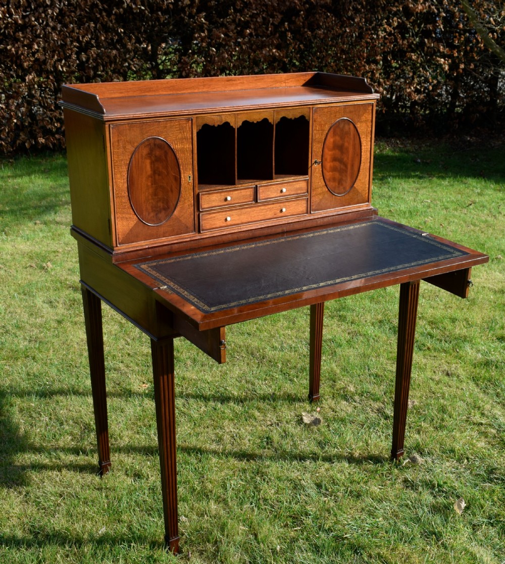 An Edwardian mahogany writing desk featuring a top superstructure with pigeonholes, cupboards, and small drawers above two frieze drawers on fluted tapered legs. View XX