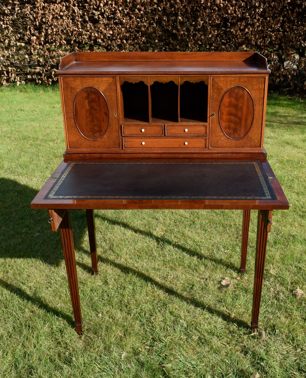 An Edwardian mahogany writing desk featuring a top superstructure with pigeonholes, cupboards, and small drawers above two frieze drawers on fluted tapered legs. View XXIII