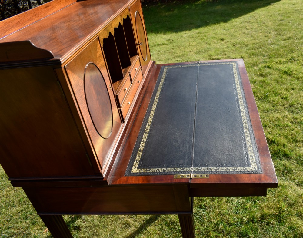 An Edwardian mahogany writing desk featuring a top superstructure with pigeonholes, cupboards, and small drawers above two frieze drawers on fluted tapered legs. View XXV