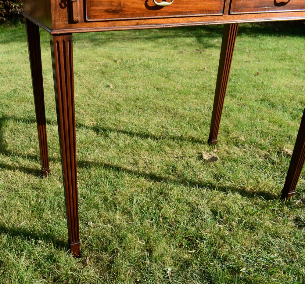 An Edwardian mahogany writing desk featuring a top superstructure with pigeonholes, cupboards, and small drawers above two frieze drawers on fluted tapered legs. View XXVII