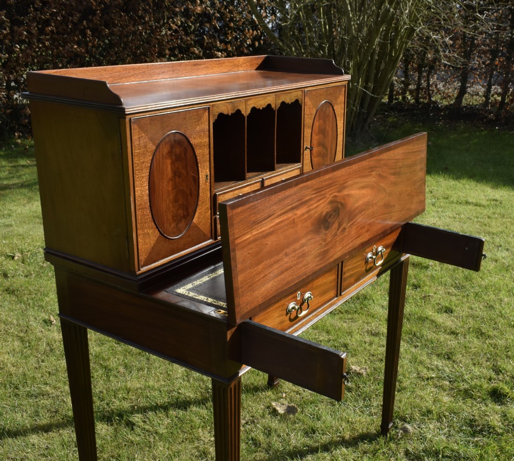 An Edwardian mahogany writing desk featuring a top superstructure with pigeonholes, cupboards, and small drawers above two frieze drawers on fluted tapered legs. View XXXI