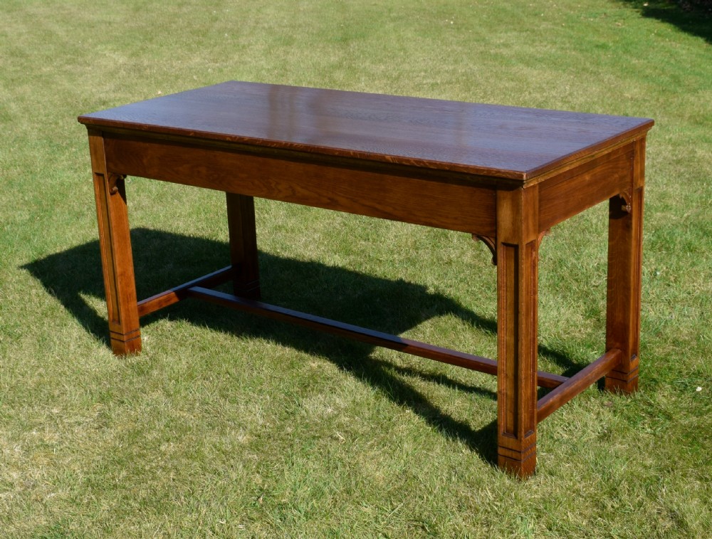 An early 20th-century warm brown rectangular oak dining table featuring square legs with carved detailing and a central low stretcher frame. View II