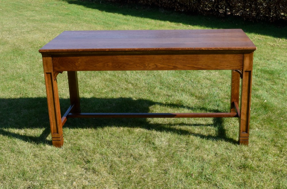 An early 20th-century warm brown rectangular oak dining table featuring square legs with carved detailing and a central low stretcher frame. View III
