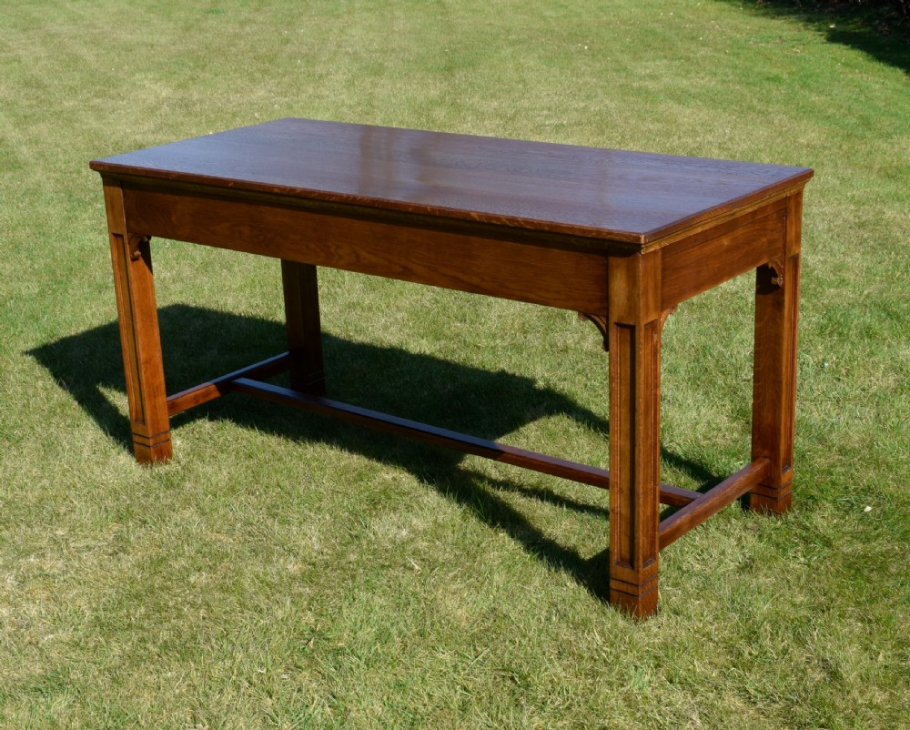 An early 20th-century warm brown rectangular oak dining table featuring square legs with carved detailing and a central low stretcher frame. View V