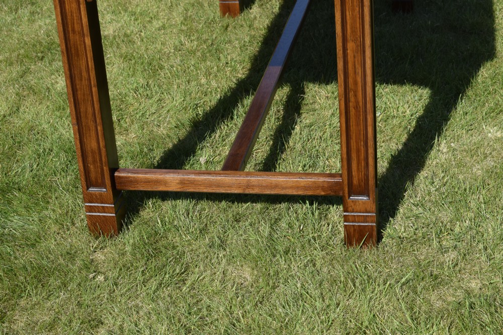An early 20th-century warm brown rectangular oak dining table featuring square legs with carved detailing and a central low stretcher frame. View VI