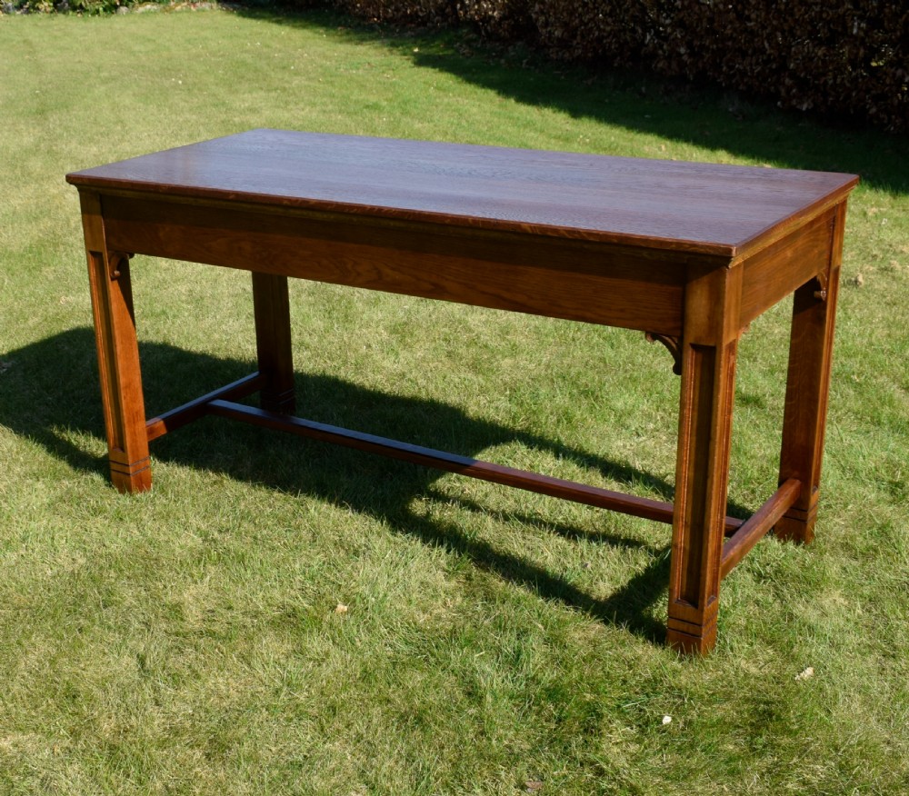 An early 20th-century warm brown rectangular oak dining table featuring square legs with carved detailing and a central low stretcher frame. View VIII
