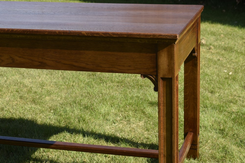 An early 20th-century warm brown rectangular oak dining table featuring square legs with carved detailing and a central low stretcher frame. View IX