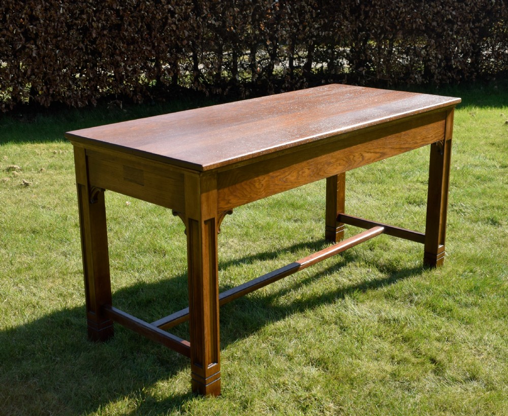 An early 20th-century warm brown rectangular oak dining table featuring square legs with carved detailing and a central low stretcher frame. View XII