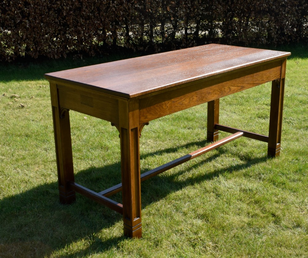 An early 20th-century warm brown rectangular oak dining table featuring square legs with carved detailing and a central low stretcher frame. View XIII