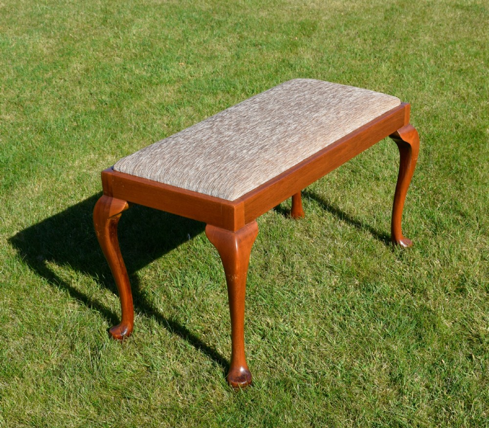 An early 20th-century duet stool with a woven fabric seat and warm brown mahogany cabriole legs. View II
