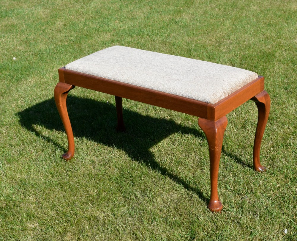 An early 20th-century duet stool with a woven fabric seat and warm brown mahogany cabriole legs. View V