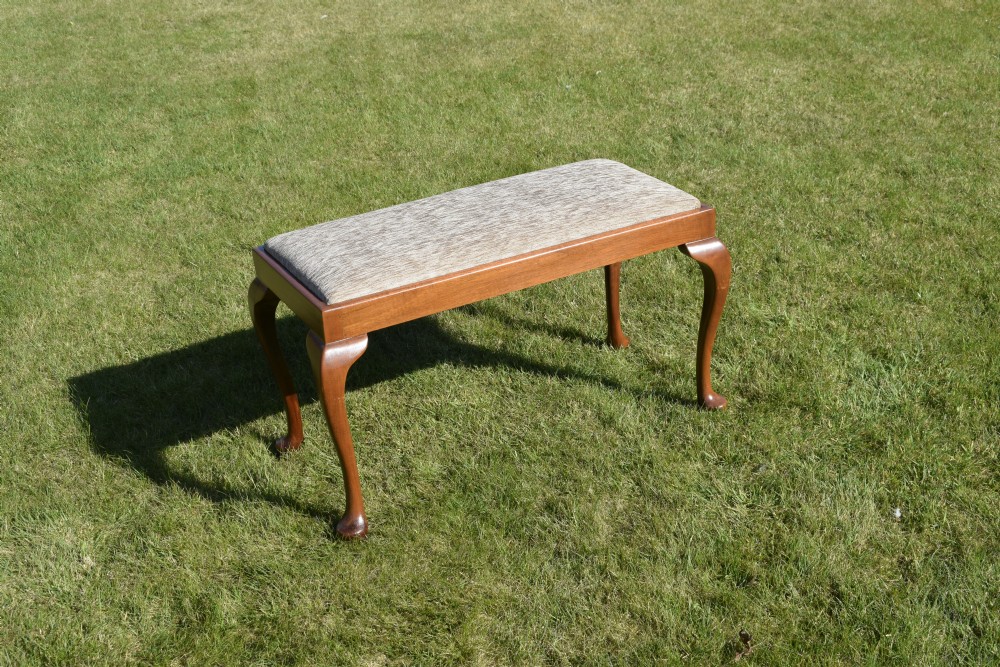An early 20th-century duet stool with a woven fabric seat and warm brown mahogany cabriole legs. View VII