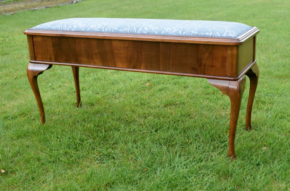 An elongated rectangular wooden duet piano stool featuring cabriole legs and a blue patterned damask upholstered seat trimmed with dark braid. View V