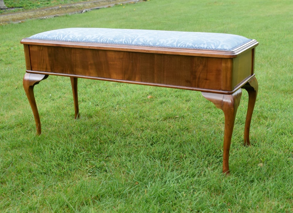 An elongated rectangular wooden duet piano stool featuring cabriole legs and a blue patterned damask upholstered seat trimmed with dark braid. View VI