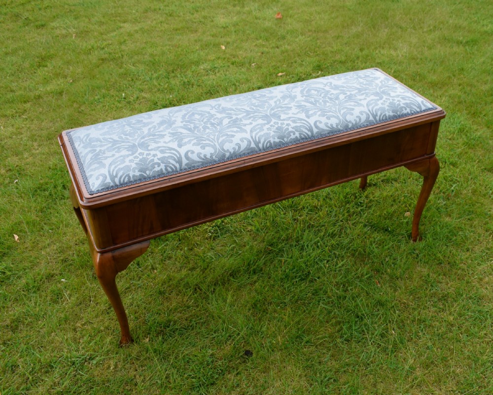 An elongated rectangular wooden duet piano stool featuring cabriole legs and a blue patterned damask upholstered seat trimmed with dark braid. View X