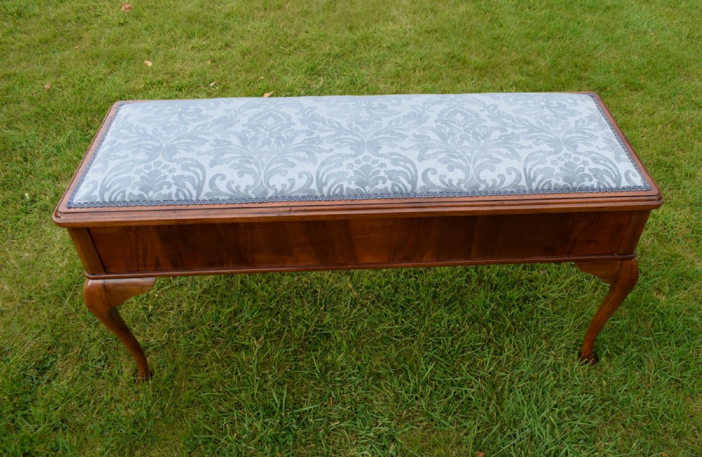An elongated rectangular wooden duet piano stool featuring cabriole legs and a blue patterned damask upholstered seat trimmed with dark braid. View XIV