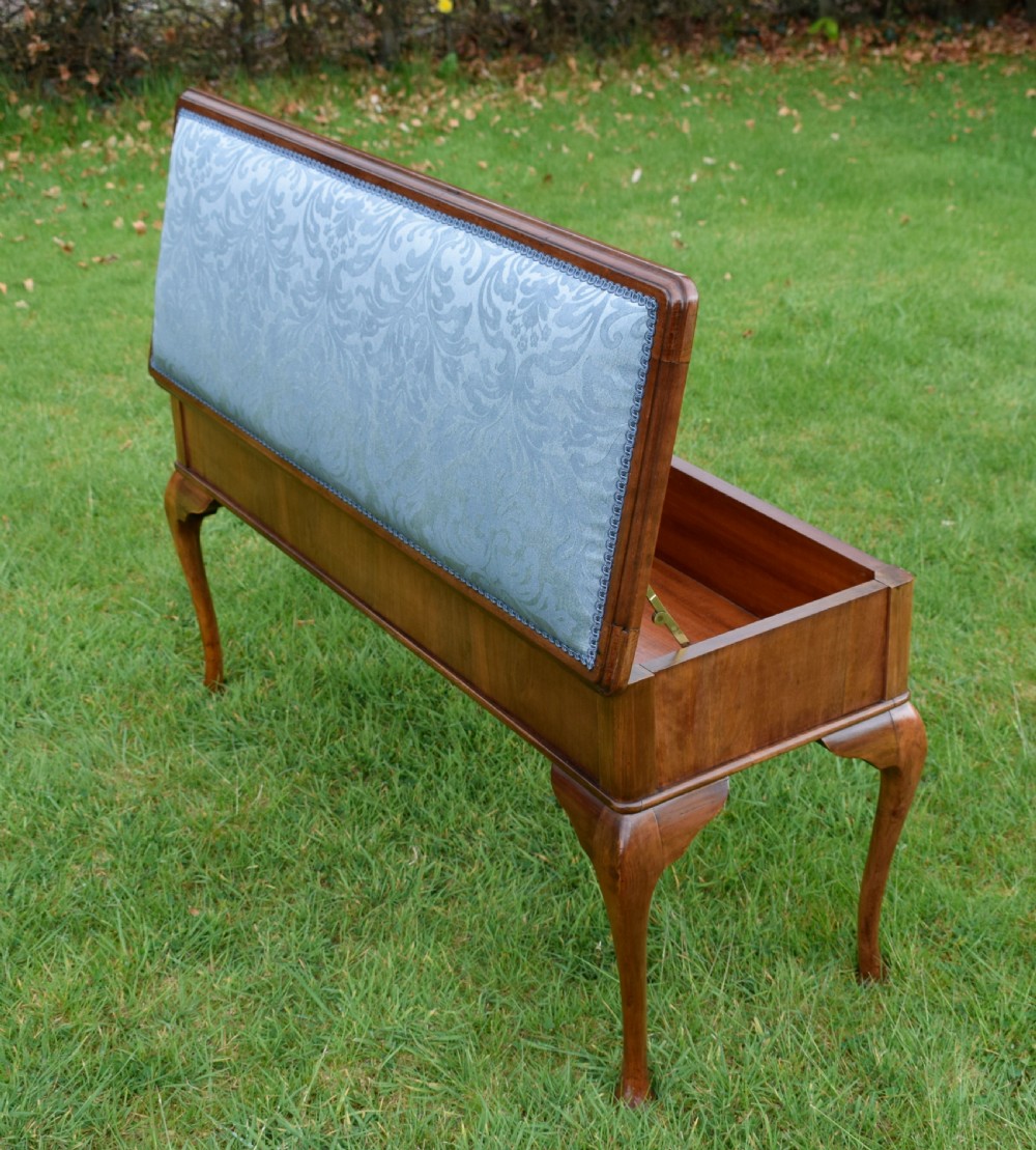 An elongated rectangular wooden duet piano stool featuring cabriole legs and a blue patterned damask upholstered seat trimmed with dark braid. View XXI