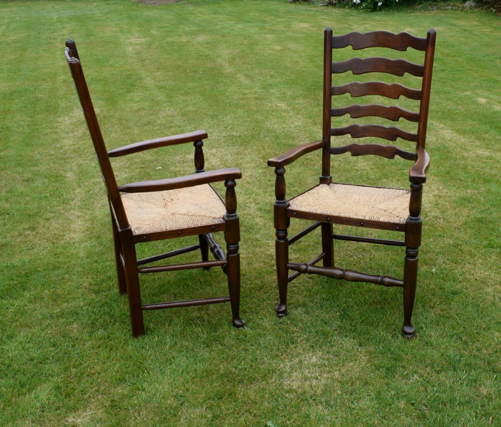 A pair of dark oak ladder back armchairs featuring woven rush seats, curved armrests, and turned front legs. View VIII