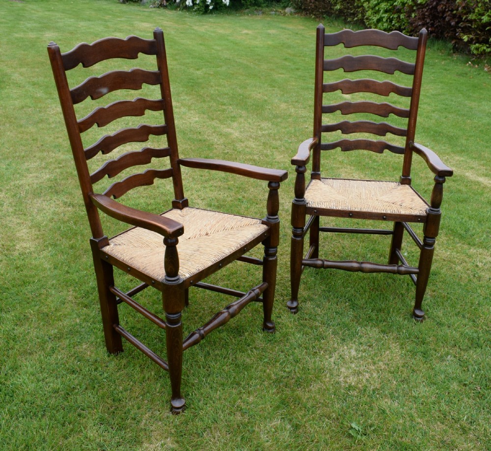 A pair of dark oak ladder back armchairs featuring woven rush seats, curved armrests, and turned front legs. View XI
