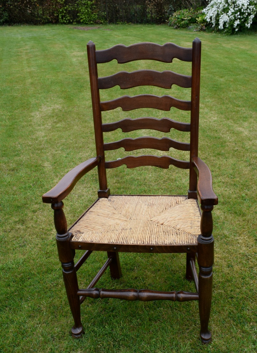 A pair of dark oak ladder back armchairs featuring woven rush seats, curved armrests, and turned front legs. View XVIII