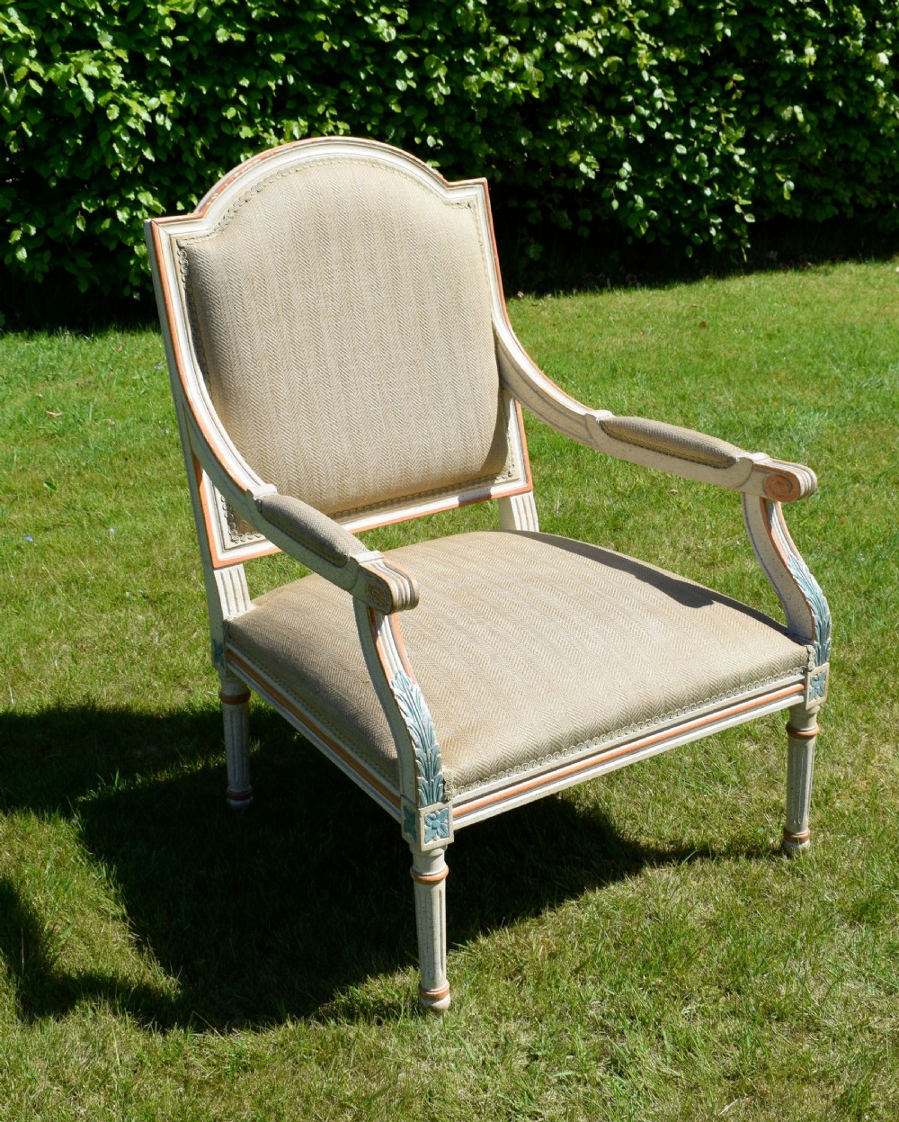 An early 20th-century French Louis XVI style fauteuil armchair featuring a painted off-white frame with fluted legs and beige herringbone fabric upholstery. View XVI