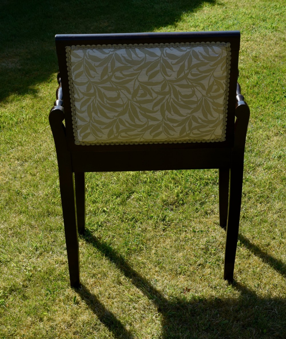 An Edwardian dark mahogany music stool featuring turned side handles, a geometric floral marquetry inlay on the frame, straight tapered legs, and a cream upholstered padded seat. View XI