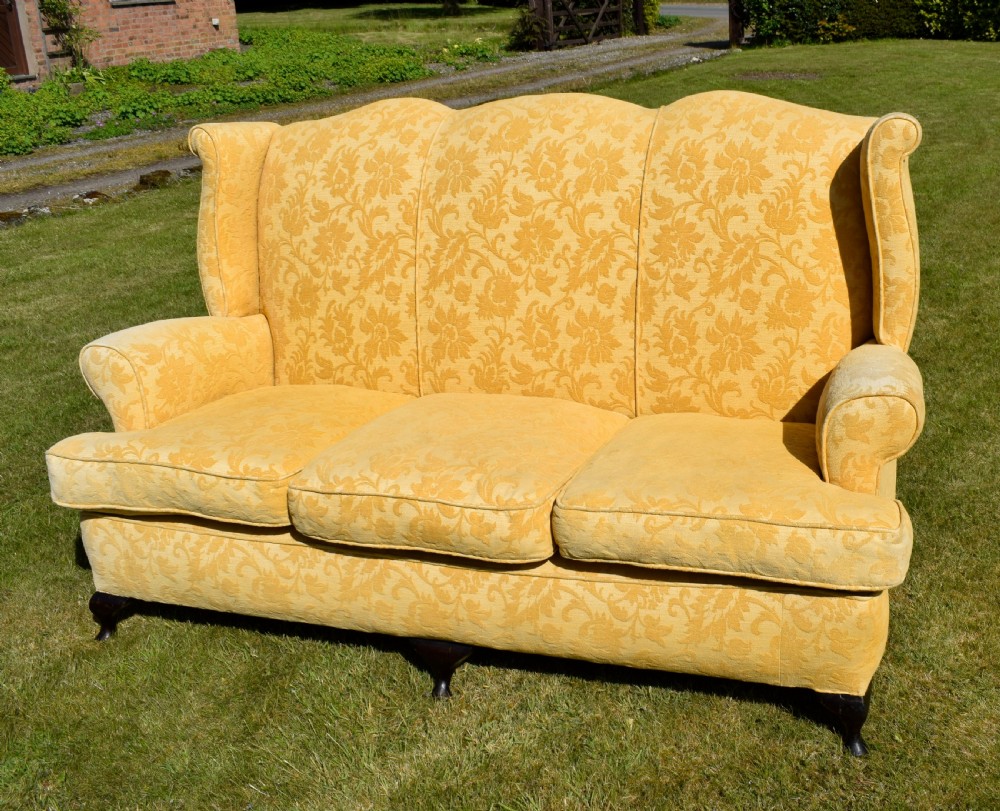 An early 20th-century Georgian style three-seater settee upholstered in yellow floral damask fabric with a serpentine crest back and scrolled arms. View II