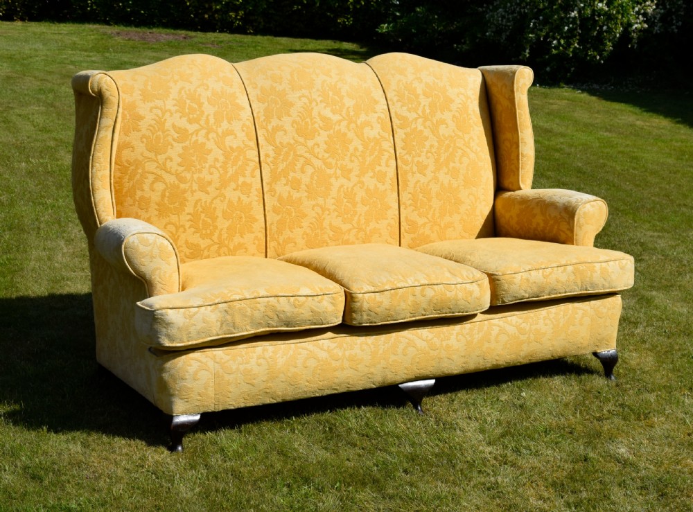 An early 20th-century Georgian style three-seater settee upholstered in yellow floral damask fabric with a serpentine crest back and scrolled arms. View V
