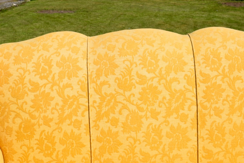 An early 20th-century Georgian style three-seater settee upholstered in yellow floral damask fabric with a serpentine crest back and scrolled arms. View XI