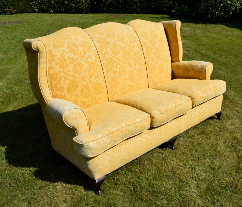 An early 20th-century Georgian style three-seater settee upholstered in yellow floral damask fabric with a serpentine crest back and scrolled arms. View XV