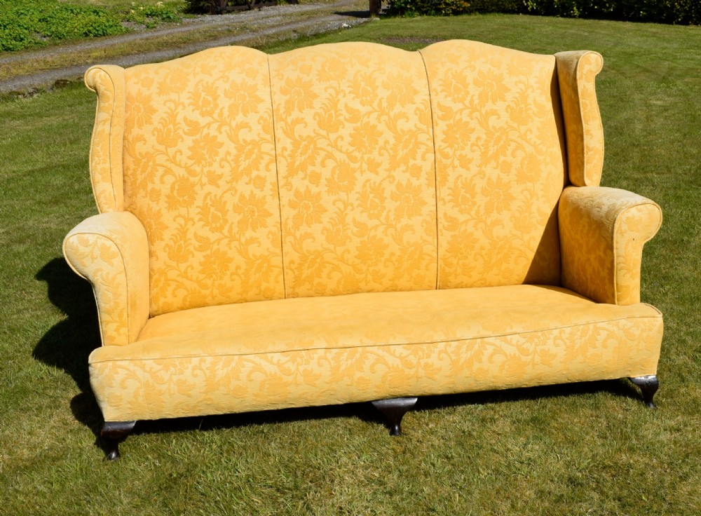 An early 20th-century Georgian style three-seater settee upholstered in yellow floral damask fabric with a serpentine crest back and scrolled arms. View XXI