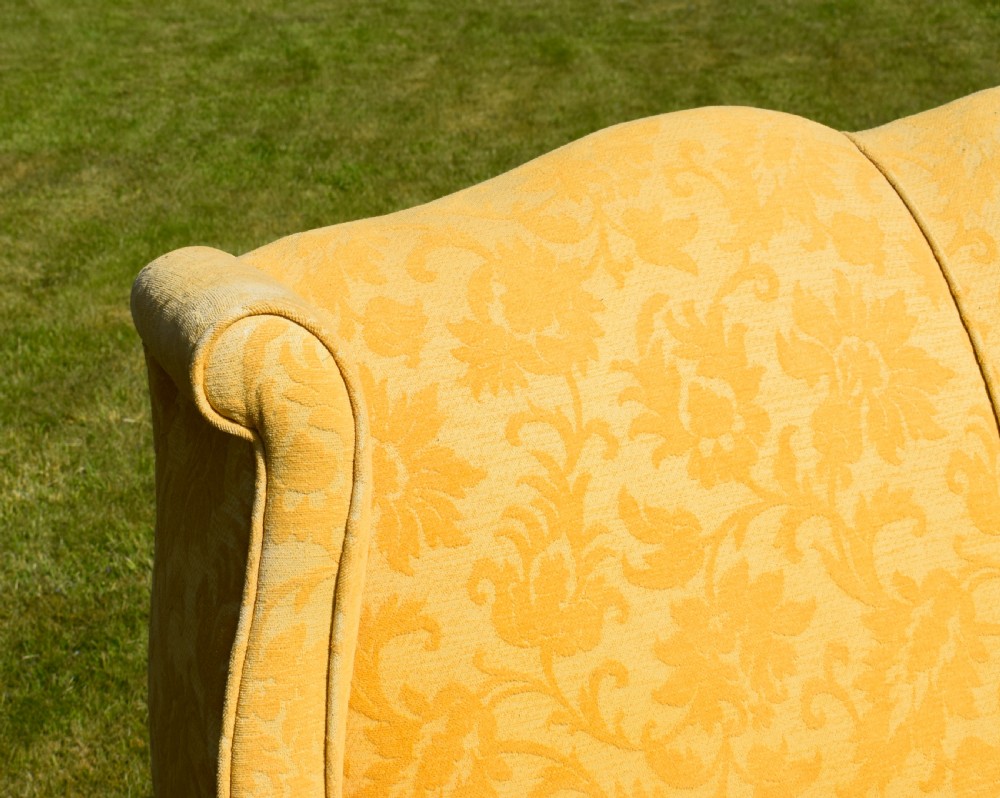 An early 20th-century Georgian style three-seater settee upholstered in yellow floral damask fabric with a serpentine crest back and scrolled arms. View XXIII